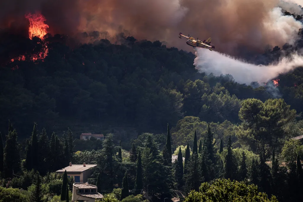 A French Civil Security Canadair CL-415 aircraft sprays water on a forest surrounding Cotignac, southeastern France on July 23, 2026 during a wildfire. The fierce fire that struck the Var region and has burned across 2,500 hectares remains stable on Jul