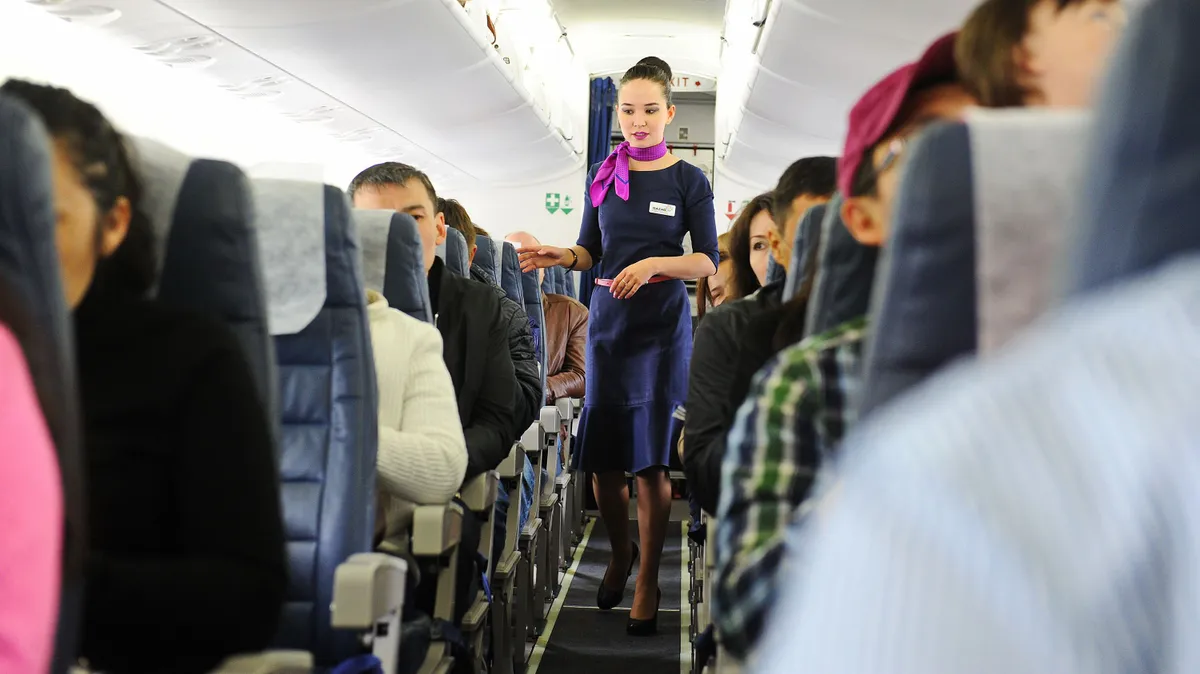 Almaty, Kazakhstan - 05.06.2016 : A flight attendant checks passengers after boarding.
