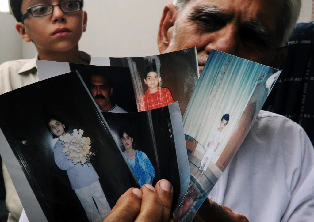 Grief-stricken Pakistani grandfather Abdul Ghani, 70, holds photographs of his son, daughter-in-law and their three children, who all died in the Airblue ED 202 plane crash, at his house in Karachi on July 28, 2010. Pakistan has declared a day of national mourning and called off a cabinet meeting after a passenger jet with 150 on board crashed into hills outside the capital Islamabad. AFP PHOTO/Asif HASSAN (Photo by ASIF HASSAN / AFP)