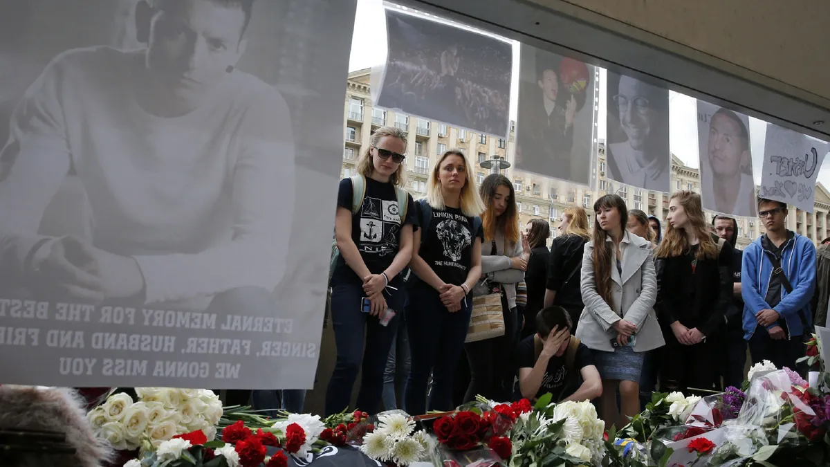 People stand near flowers laid in memory of Linkin Park frontman Chester Bennington in front of the US embassy in central Moscow on July 22, 2017. Linkin Park frontman Chester Bennington killed himself on the birthday of his late friend Chris Cornell of Soundgarden, highlighting the close friendship between the two troubled singers. The 41-year-old Bennington, who like Cornell had long suffered alcohol and drug problems, was found hanging at his Los Angeles home on July 20, 2017. (Photo by Maxim ZMEYEV / AFP)