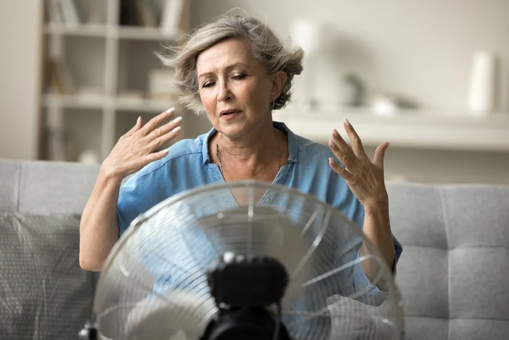 Idős nő ventilátor előtt kánikula idején