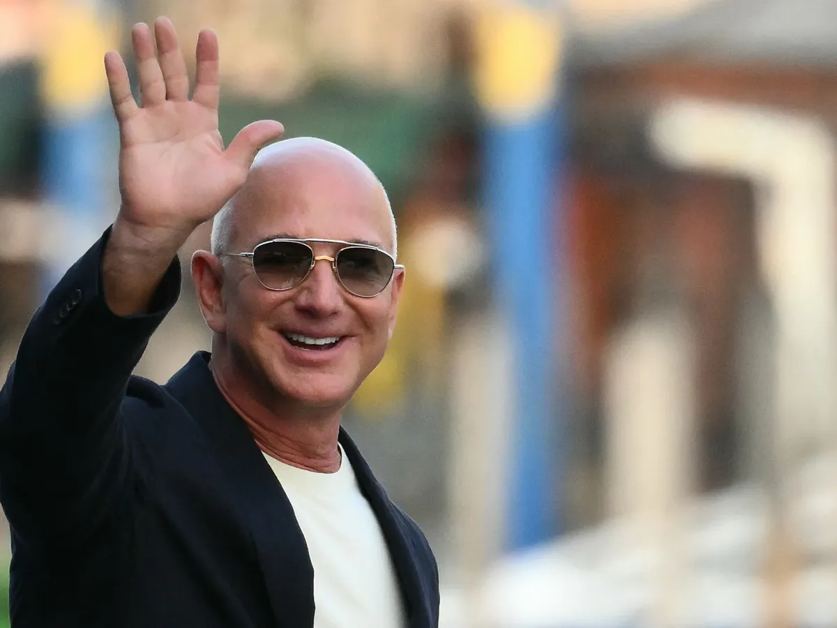 (FILES) US founder of Amazon, Jeff Bezos waves as he leaves the Aman Hotel in Venice on June 25, 2025. Liverpool's owners, August 14, have agreed to sell a minority stake in the Premier League club to a consortium including Amazon founder Jeff Bezos. (Photo by Marco BERTORELLO / AFP)