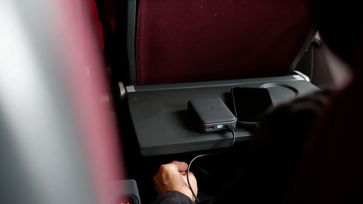 Mobiltelefon és power bank egy repülőgép tálcájára helyezve. 