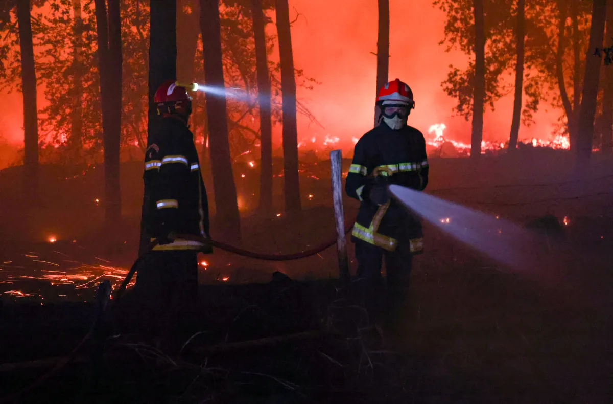 Firefighters battle the flames as a wildfire rages through the Landes forest in Luglon, southwestern France, in the early hours of August 14, 2026. The fire that broke out on August 13, 2026 in the Landes forest has now spread across 400 hectares, and 400 people "are being evacuated as a precautionary measure", according to the prefecture of this south-western department. (Photo by ROMAIN PERROCHEAU / AFP)
