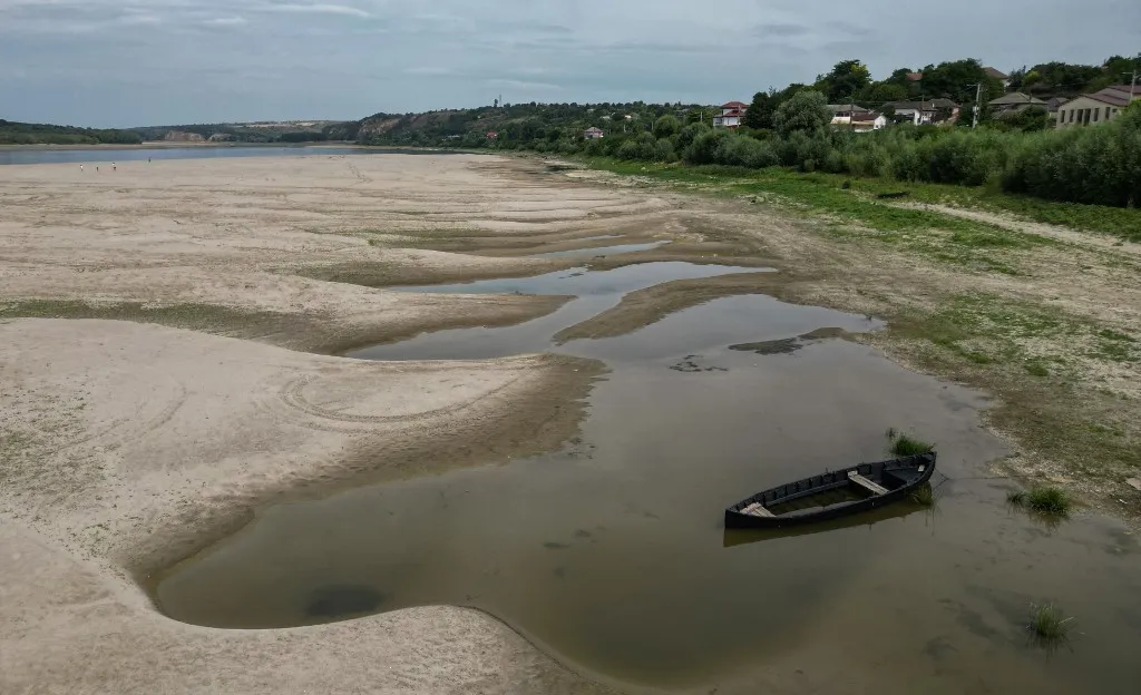 hőség, An aerial view shows a dried-out river bed of Danube in Rasova village August 3, 2026. Romanian army forces detonated an explosive load into the rock bed of Danube in Izvoarele village, kilometers away from Rasova, to help diverting a higher volume of water toward the cooling systems of the Cernavoda Nuclear Power Plant. Local authorities and plant engineers authorized the blasting operations to counteract critically low water levels caused by a prolonged summer heatwave, ensuring the continuous and safe operation of the facility's reactors. (Photo by Daniel MIHAILESCU / AFP)