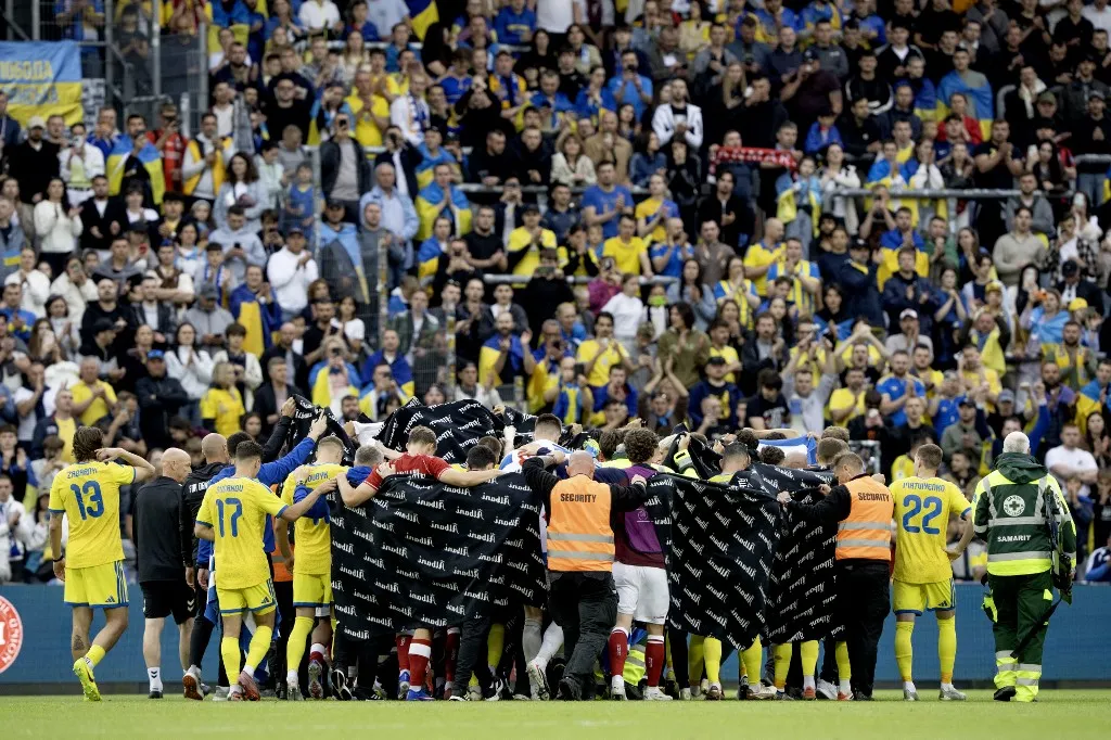 Denmark's and Ukraine's players accompany Christian Eriksen to a waiting ambulance during the football international match between Denmark and Ukraine at Odense Stadium on Sunday, June 7, 2026. (Photo: Bo Amstrup/Ritzau Scanpix) (Photo by BO AMSTRUP / Ritzau Scanpix via AFP)