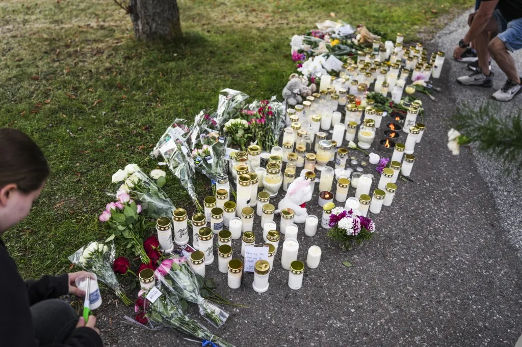 svéd rendőrség, Fagersta, kardos támadás, TikTok, svédországi iskola, rendőrségi nyomozás Virágokkal és mécsesekkel emlékeznek az iskolai támadás áldozatára a svédországi FagerstábanFAGERSTA, SWEDEN 20260822Fagersta residents leave flowers and candles at a makeshift memorial outside a shool in Fagersta, Sweden, on Aug. 22, 2026, the day after a 17-year-old girl was killed and three others injured at the school by a man with a sword. Photo: Magnus Lejhall / TT / Code 10658 (Photo by Magnus Lejhall / TT News Agency via AFP)