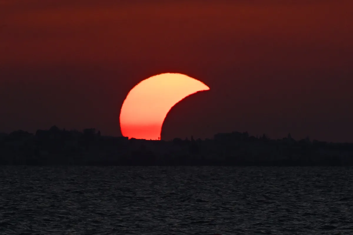 A partial solar eclipse is seen at Soliman Beach in Tunisia's Nabeul province on August 12, 2026. One of nature's greatest spectacles –- a rare total solar eclipse –- cast its shadow on August 12, briefly turning day into night in Russia's remote Arctic north and western Iceland before heading towards mainland Europe. Supplies of special viewing glasses were in high demand, with huge crowds turning out to watch a partial eclipse across Europe, with the event also visible in Canada, the northern United States and northwest Africa. (Photo by FETHI BELAID / AFP)
