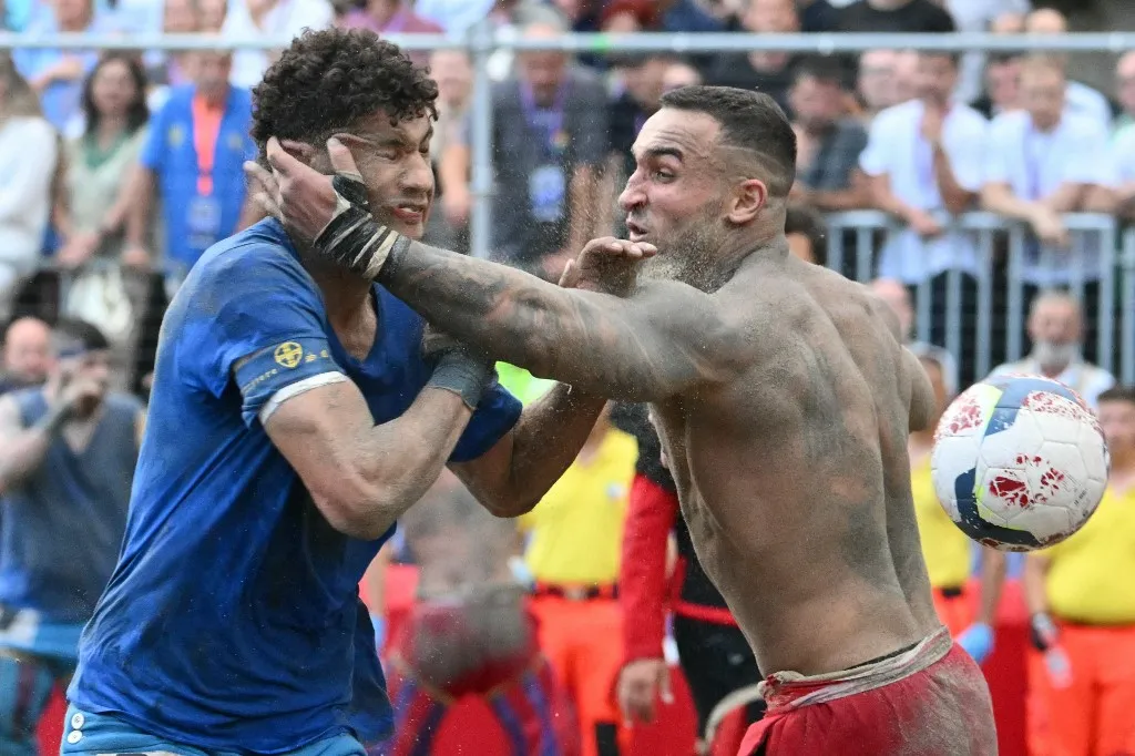 Players fight during the final match of the Calcio Storico Fiorentino, a traditional 16th century renaissance ball game, between the Azzurri of Santa Croce and the Rossi of Santa Maria Novella, at Piazza Santa Croce in Florence on June 24, 2026. (Photo by Alberto PIZZOLI / AFP)