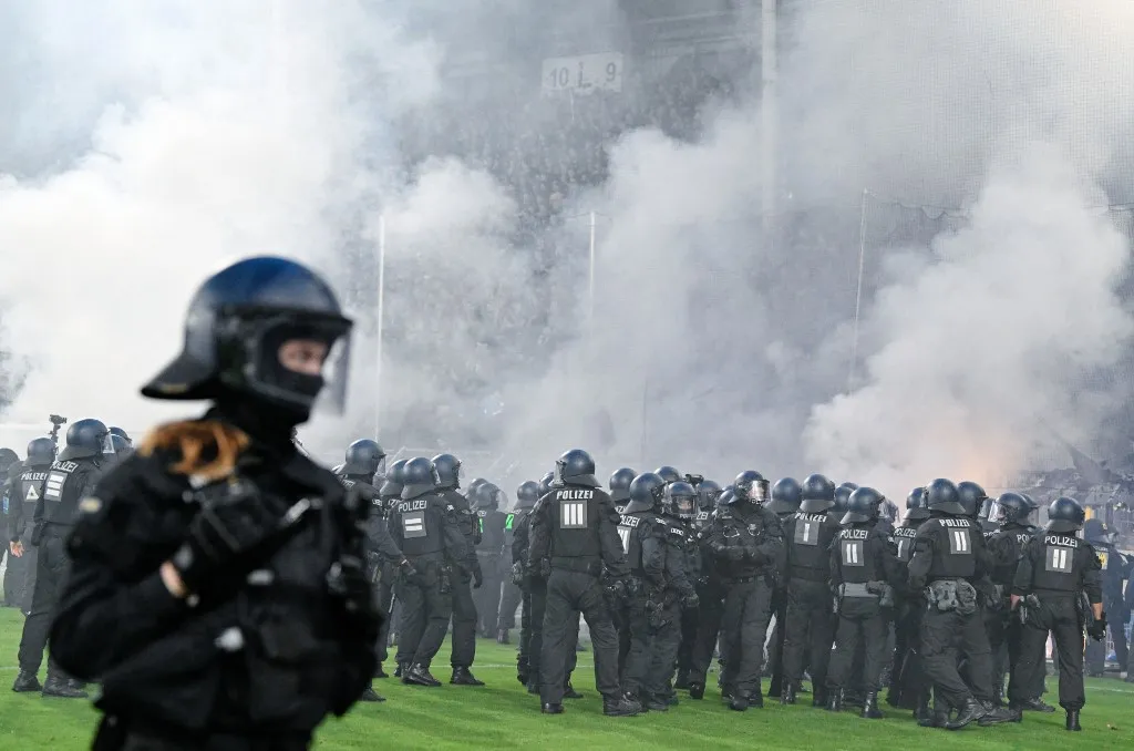 Pirotechnikai eszközöket is használtak a futballhuligánok a Német Kupa mérkőzésén dpatop - 21 August 2026, Baden-Württemberg, Mannheim: Soccer, Men: DFB Cup, SV Waldhof Mannheim vs. 1. FC Kaiserslautern, First Round, Carl-Benz-Stadion. Police officers stand in front of the SV Waldhof Mannheim fan section. Photo: Uwe Anspach/dpa - IMPORTANT NOTICE: In accordance with the regulations of the Bundesliga and the DFB (German Football Association), it is prohibited to use or allow the use of photographs taken in the stadium and/or during the game in the form of sequential images and/or video-like photo series. (Photo by UWE ANSPACH / dpa Picture-Alliance via AFP)