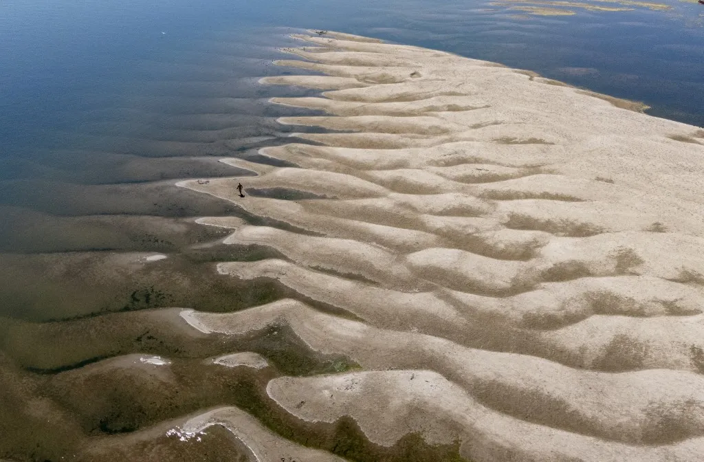A Duna alacsony vízállása a horvátországi Batinánál 2026. augusztus 9-én. A hőhullám hatása Európa több folyóján is megmutatkozik. This aerial photograph shows a man walking on the sandbanks exposed by the receding waters of the Danube river in Batina, northeastern Croatia on August 9, 2026. (Photo by MARKO PERKOV / AFP)