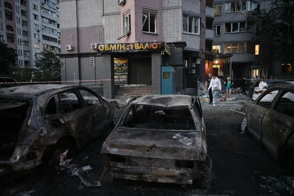 Local residents attend outside a multi-storey residential building damaged following massive Russian ballistic missile strikes in the Ukrainian capital of Kyiv on August 1, 2026, amid the Russian invasion in Ukraine. The death toll from Russian strikes on Kyiv has risen to nine, Ukraine's emergency service said. (Photo by Genya Savilov / AFP), Ukrajna, Kijev, orosz rakétatámadás