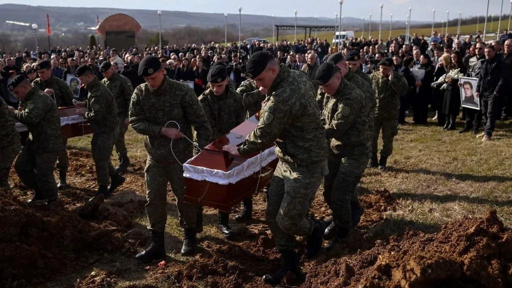 Újabb tömegsír feltárása kezdődött Koszovóban. A koszovói háborúban mintegy 13 ezren haltak meg, 1600 embert pedig ma is eltűntként tartanak nyilván.,Members of the Kosovo Security Force lower the coffins of Bali Gashi, Fadil Elezi and Masar Dushi, whom remains were recently recovered from a mass grave, during a funeral ceremony near the town of Klina on February 27, 2026. For over a week, forensic teams have been exhuming remains at the Perzhina site in southern Kosovo, the latest in hundreds of mass graves uncovered since the country's 1998-1999 war with Serbia ended. The conflict between independence-seeking ethnic Albanian guerrillas and Serbian forces killed around 13,000 people and left 4,000 missing. (Photo by AFP)