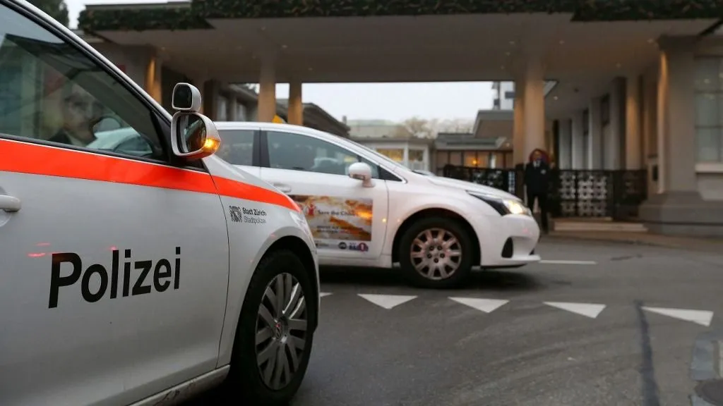 lövés, A police car is driving on December 3, 2015 in front of the entrance of the Hotel Baur au Lac in Zurich, where Swiss authorities have conducted an early-morning operation to arrest several FIFA football officials. The Swiss government said two FIFA officials were detained in Zurich on December 3 ,confirming reports of newarrests in the broadening FIFA scandal, and said they were suspected of accepting millions of dollars in bribes. (Photo by MICHELE LIMINA / AFP)