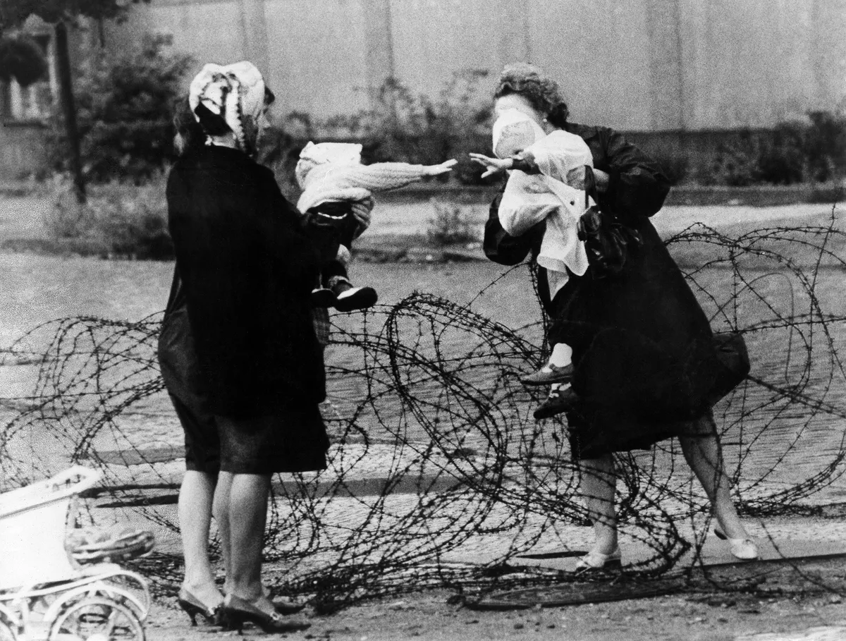 (GERMANY OUT) Germany / GDR. Construction of the wall. Mothers with children separated by barbwire. Berlin August 1961 (Photo by Hilde/ullstein bild via Getty Images)