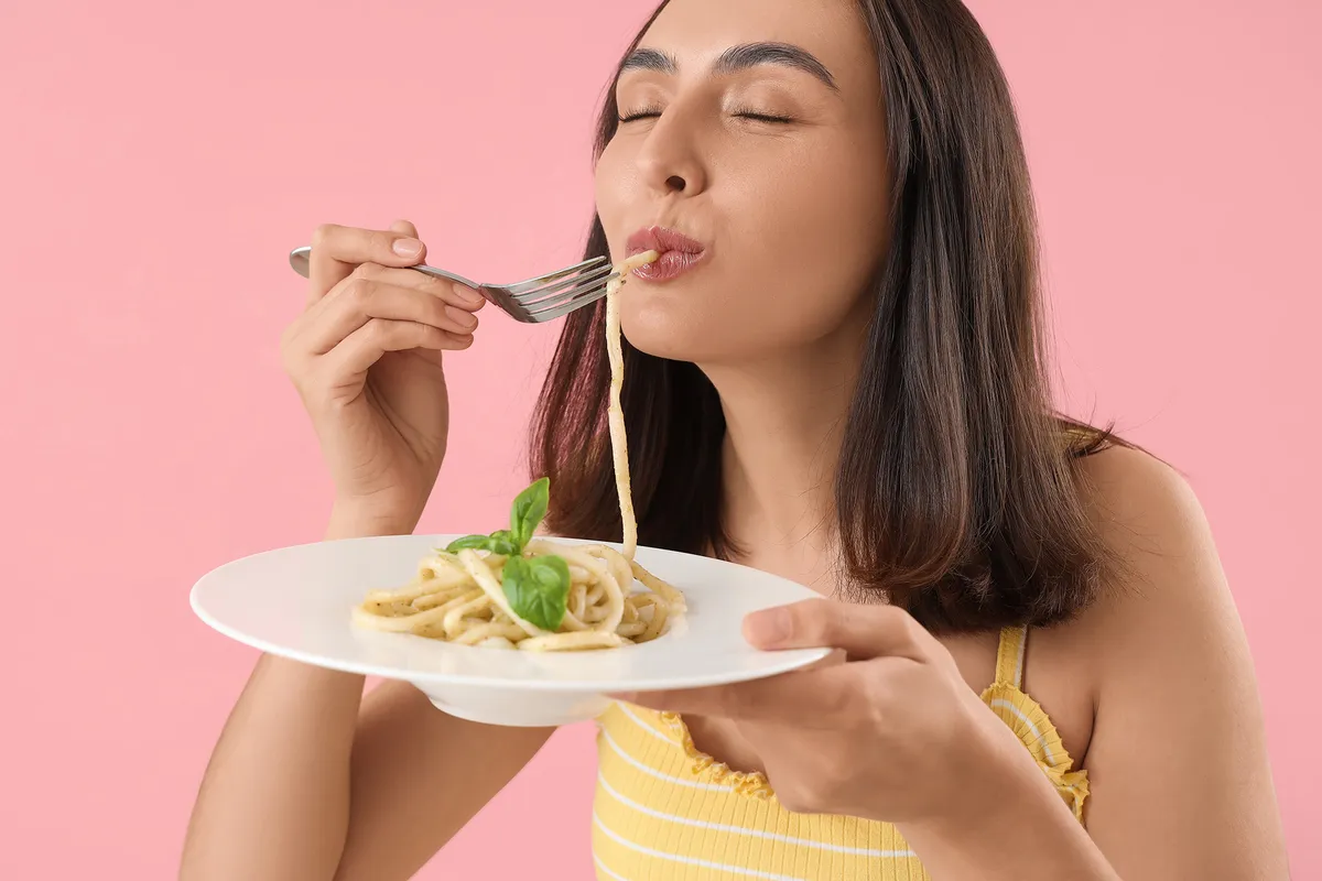 A képen egy nő látható, aki al dente tészta főzés közben megkóstolja a finom falatokat.