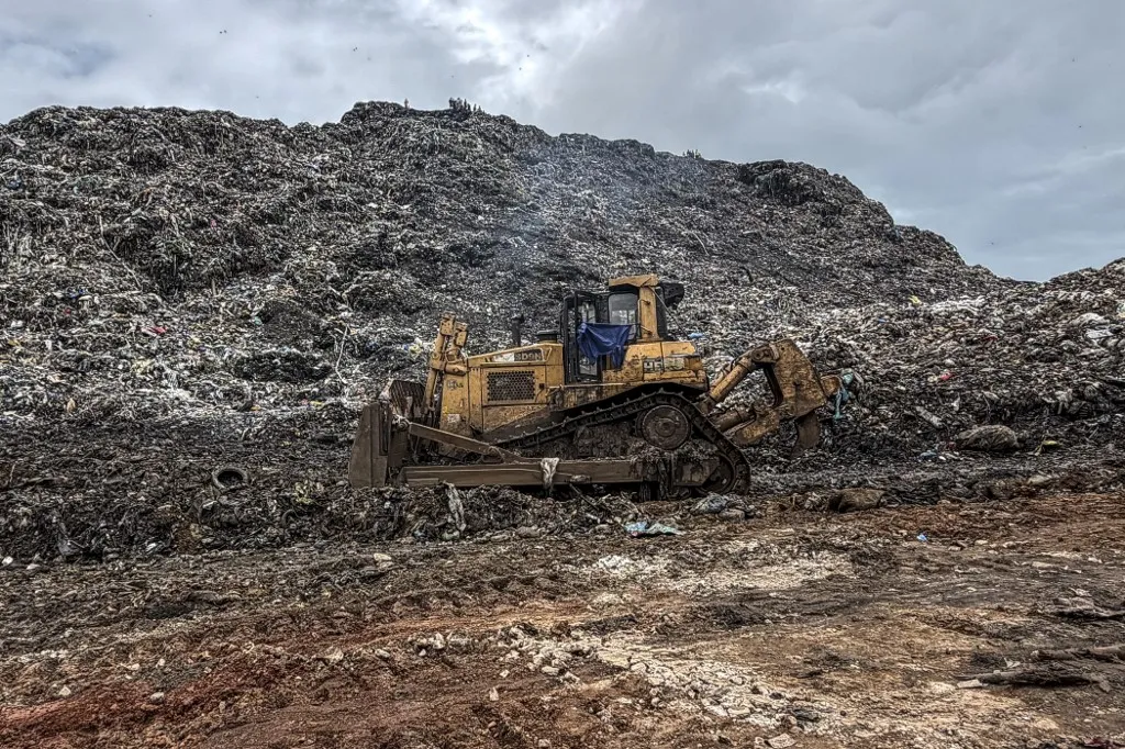 An bulldozer is seen at the Dar es Salaam dumpsite after it was struck by a landslide overnight in Conakry on August 23, 2026. Thirty people died and six were seriously wounded Sunday on the outskirts of Conakry, Guinea's capital, after a mound of rubbish in a landfill collapsed onto homes following heavy rains, said a government statement.
The accident happened at 2:00 am (0200 GMT) Sunday morning, at the Dar-es-salam neighbourhood in the Bbessia district, said the government statement. (Photo by AFP)