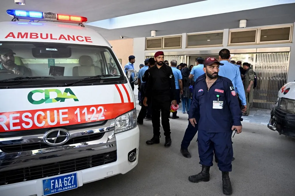Security personnel stand next to an ambulance following a fire incident outside the Mother and Child Health (MCH) ward at the Pakistan Institute of Medical Sciences (PIMS) Hospital in Islamabad on August 26, 2026. A fire erupted in a maternity ward in Pakistan's capital on August 26, killing 14 children, the Islamabad district office said. (Photo by Aamir QURESHI / AFP)