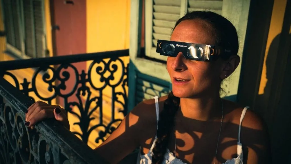 Illustrative photo of a young woman sitting on the balcony of her flat in Nices Old Port, wearing protective glasses for the solar eclipse scheduled for 12 August 2026, Daily illustration made in Nice, France on August 2, 2026. (Photo by Amaury Cornu / Hans Lucas via AFP)