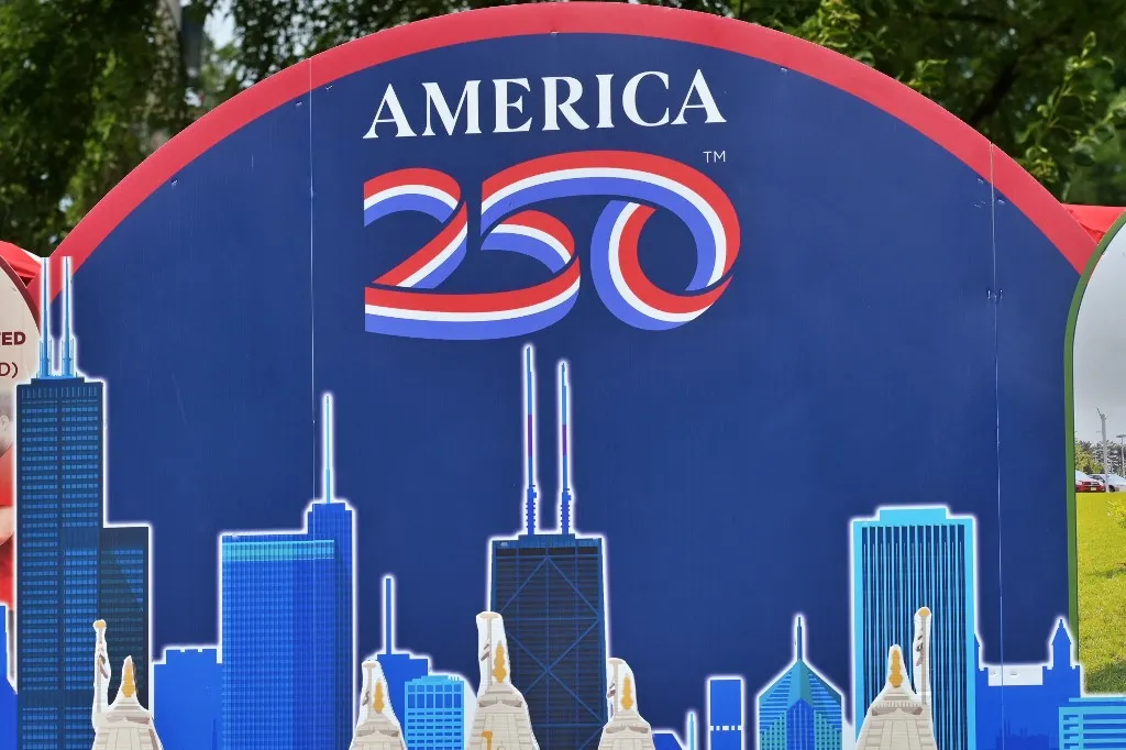 DES PLAINES, ILLINOIS - JULY 04: A close-up view of an 'America 250' celebratory sign featuring a stylized red, white, and blue logo above an outline of the Chicago skyline is displayed during the annual Independence Day festivities on July 4, 2026 in Des Plaines, Illinois. The parade and community events marked the United States' Semiquincentennial anniversary. Jacek Boczarski / Anadolu (Photo by Jacek Boczarski / Anadolu via AFP)