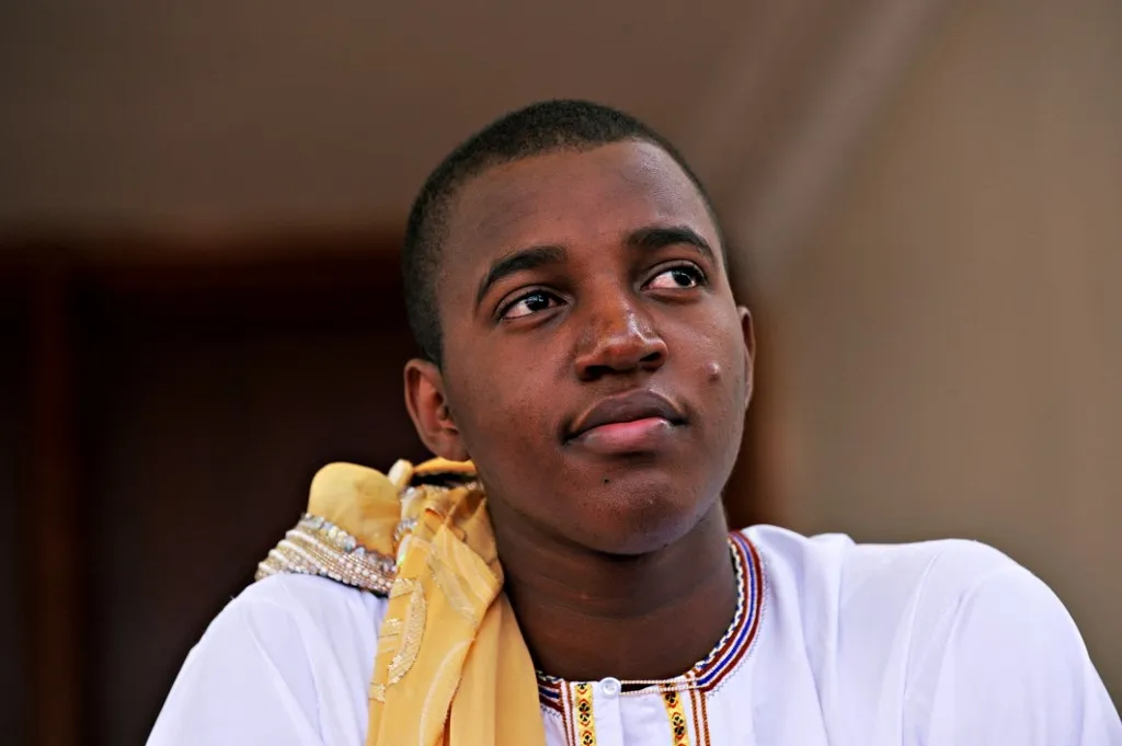 King Oyo Nyimba Kabamba Iguru Rukidi IV, looks on after his crowning ceremony in Fort Portal on April 17, 2010. The young king had officially succeeded to the throne at the age of three when his father died of a heart attack in 1995, but coronation takes place only upon reaching adulthood. Despite Oyos apparent ambivalence regarding his official duties and the anachronism of a Jay-Z loving, Arsenal-supporting 18-year-old-king banging drums and blessing spears, no one interviewed on Saturday dismissed the importance of his job, or the role of his kingdom in modern Uganda. AFP PHOTO/ROBERTO SCHMIDT (Photo by ROBERTO SCHMIDT / AFP)