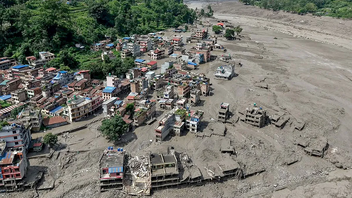 This aerial view shows houses laying partially submerged in muddy water along a riverside after flash floods at Trishuli Bazar in Nepal's Nuwakot district on August 26, 2026. A massive flood swept through Nepal's northern Rasuwa district on August 26, damaging roads and power infrastructure as authorities scrambled to assess the scale of the destruction. (Photo by Prabin RANABHAT / AFP)
