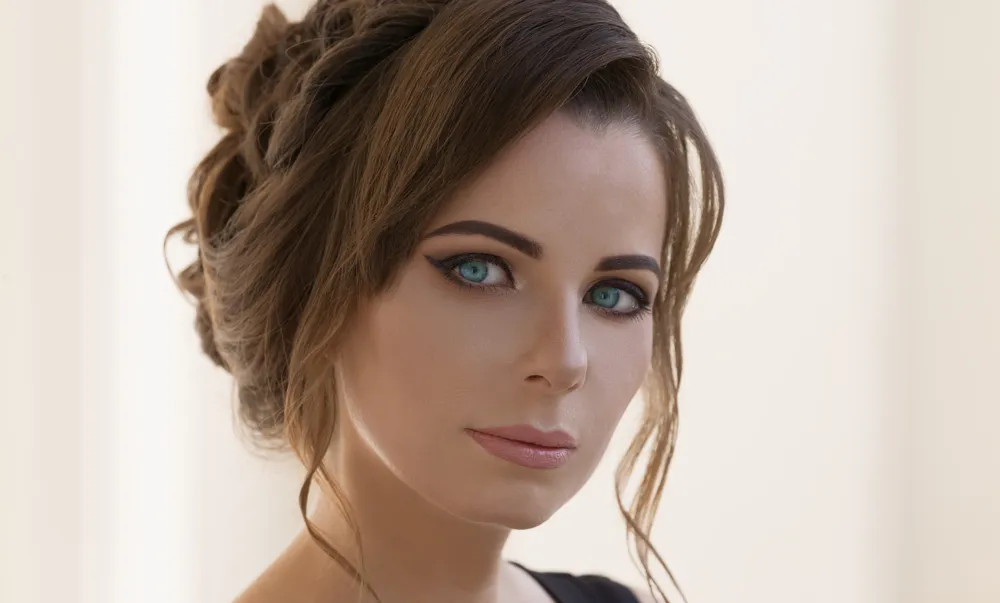 Beautiful woman, has sexy blue eyes, contact lenses, brunette hair, luxury make up, stylish hairstyle, serious face.  Portrait in white background. Fashion style makeup. Close up.