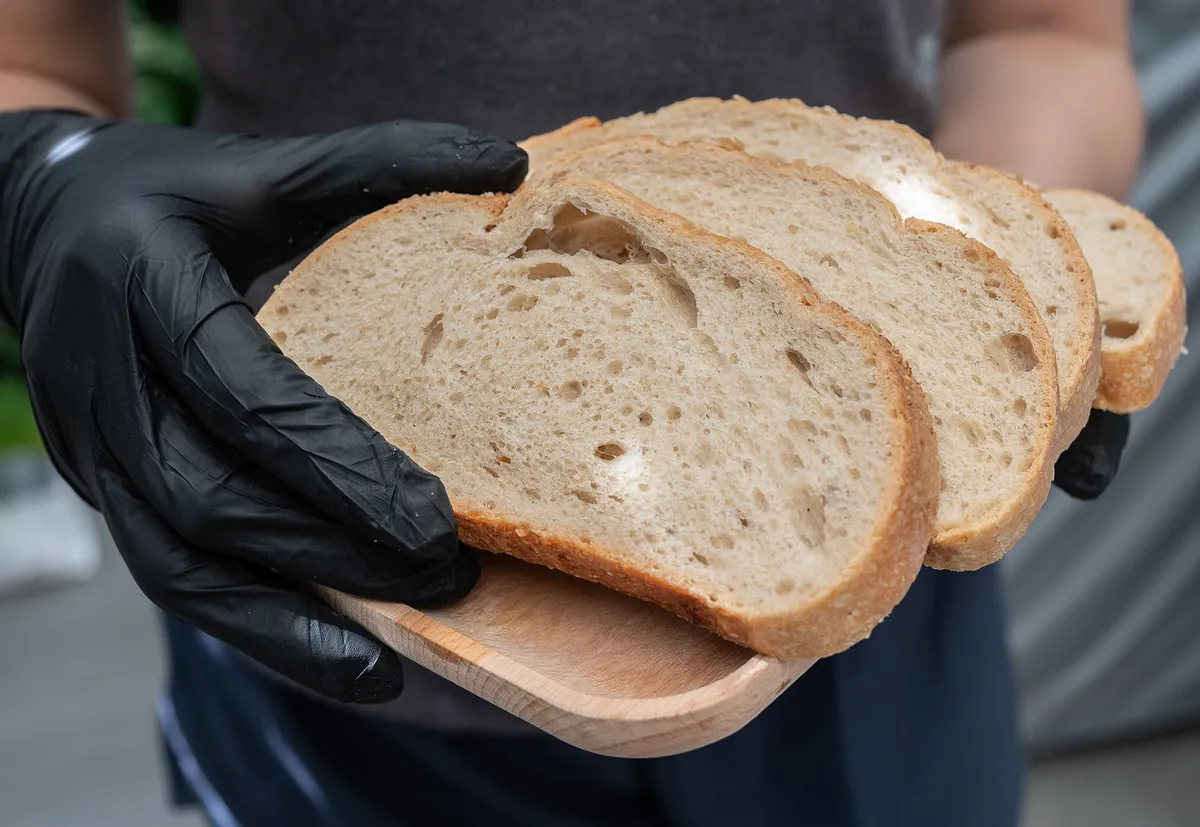 Woman holding pieces of sourdough bread after cutting before eat. Sourdough is a type of bread leavened naturally using a fermented starte a mixture of flour and water rather than commercial yeast.
