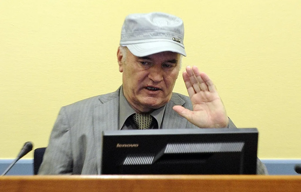 (FILES) Wartime Bosnian Serb General Ratko Mladic wearing a cap salutes in the court room at his initial appearance at the UN Yugoslav war crimes tribunal in The Hague on June 3, 2011. Former Bosnian military Serb leader and war criminal Ratko Mladic has died in a prison hopsital in the Hague, according to Serbian state broadcaster RTS on August 27, 2026, after suffering several strokes. Mladic, 84, was dubbed the "Butcher of Bosnia" for his role in the 1995 Srebrenica massacre during the Bosnian war. (Photo by MARTIN MEISSNER / POOL / AFP)