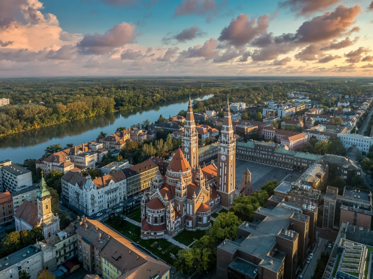 A képen Szeged látható a Dóm térrel és a Tiszával a háttérben. A kép illusztráció a magyar városok kvízhez.