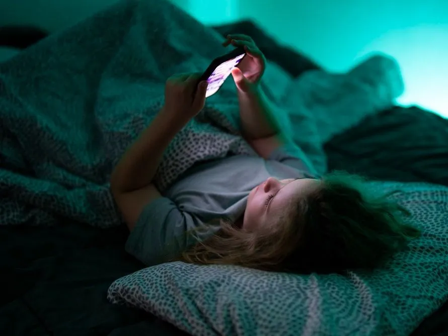 Az első telefon átadásakor a szülői kontroll és a digitális biztonság is fontos szempont gyerek este az ágyban okostelwfonnal