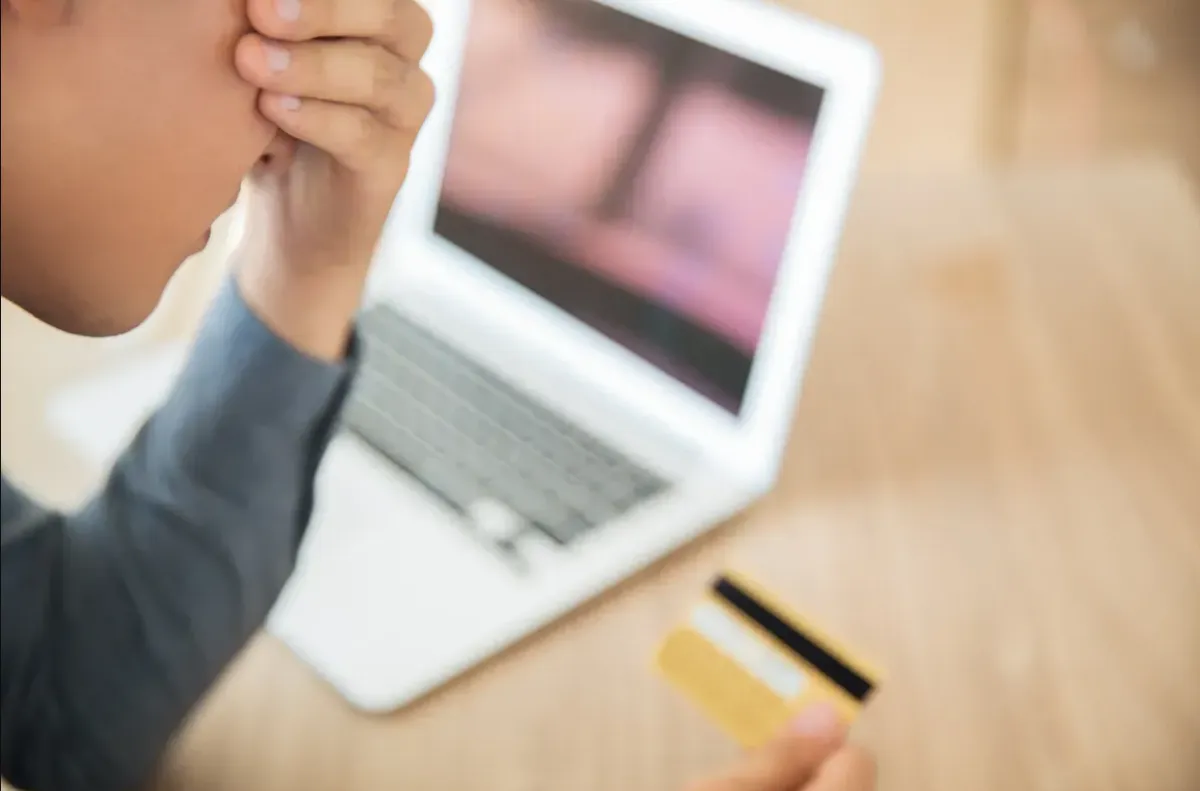Wifi gyorsításáért küzdő férfi egy laptop előtt, kezében egy bankkártyával