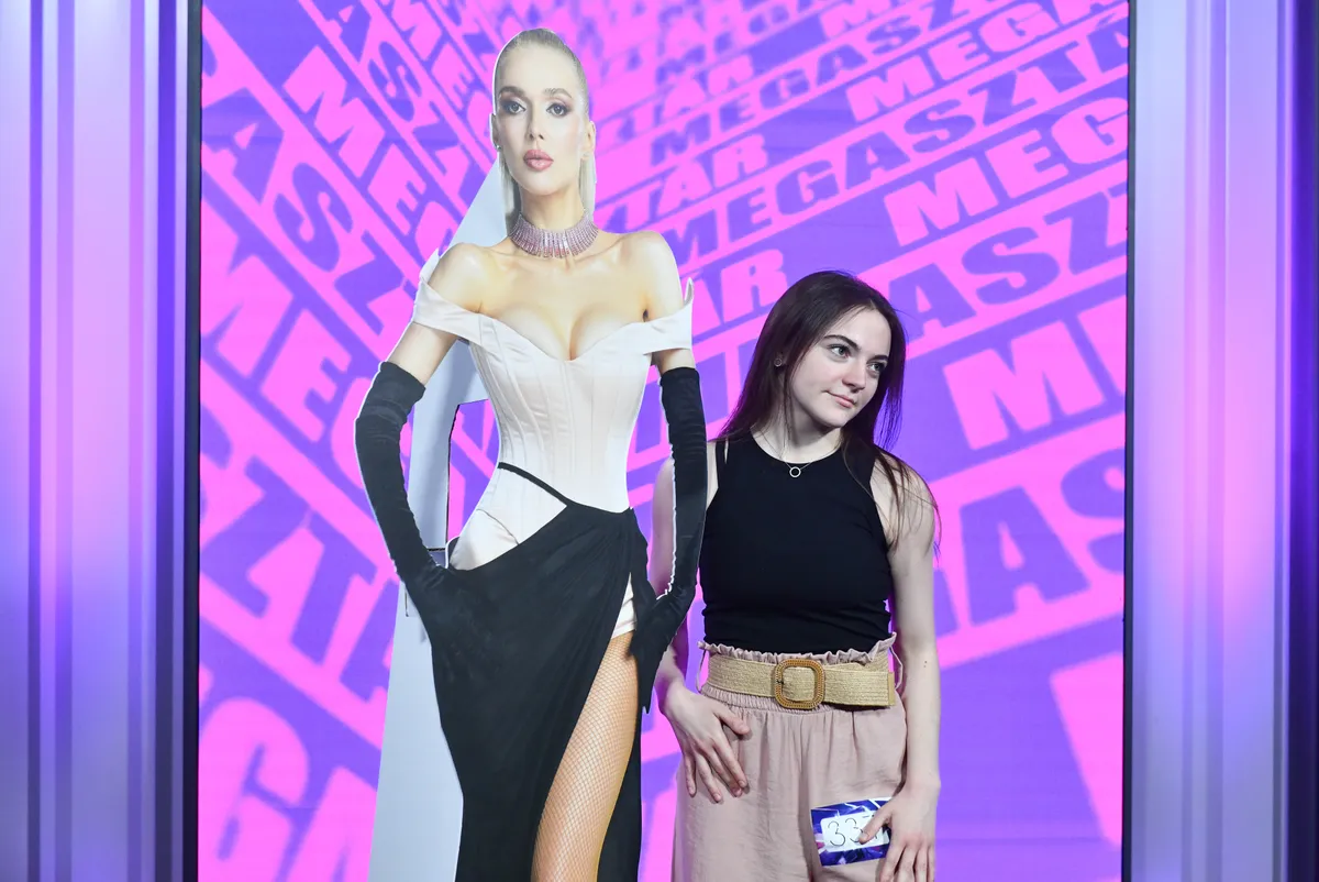 A Megasztár versenyzője egy Herceg Erika plakát mellett fotózkodik.