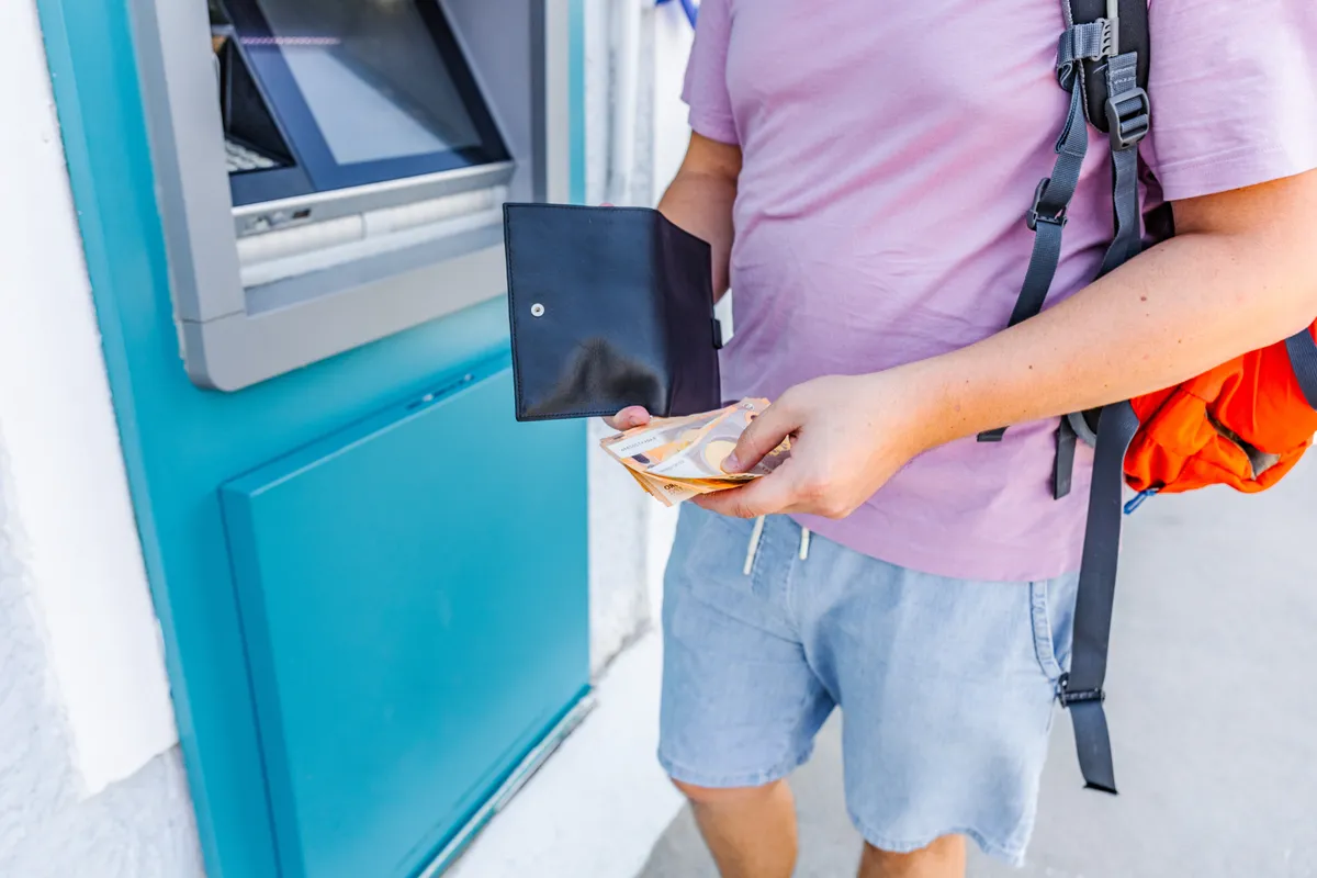 Traveler withdrawing euro cash from an ATM during vacation abroad. Travel budgeting, tourism expenses, international payments and holiday planning concept. High quality photo