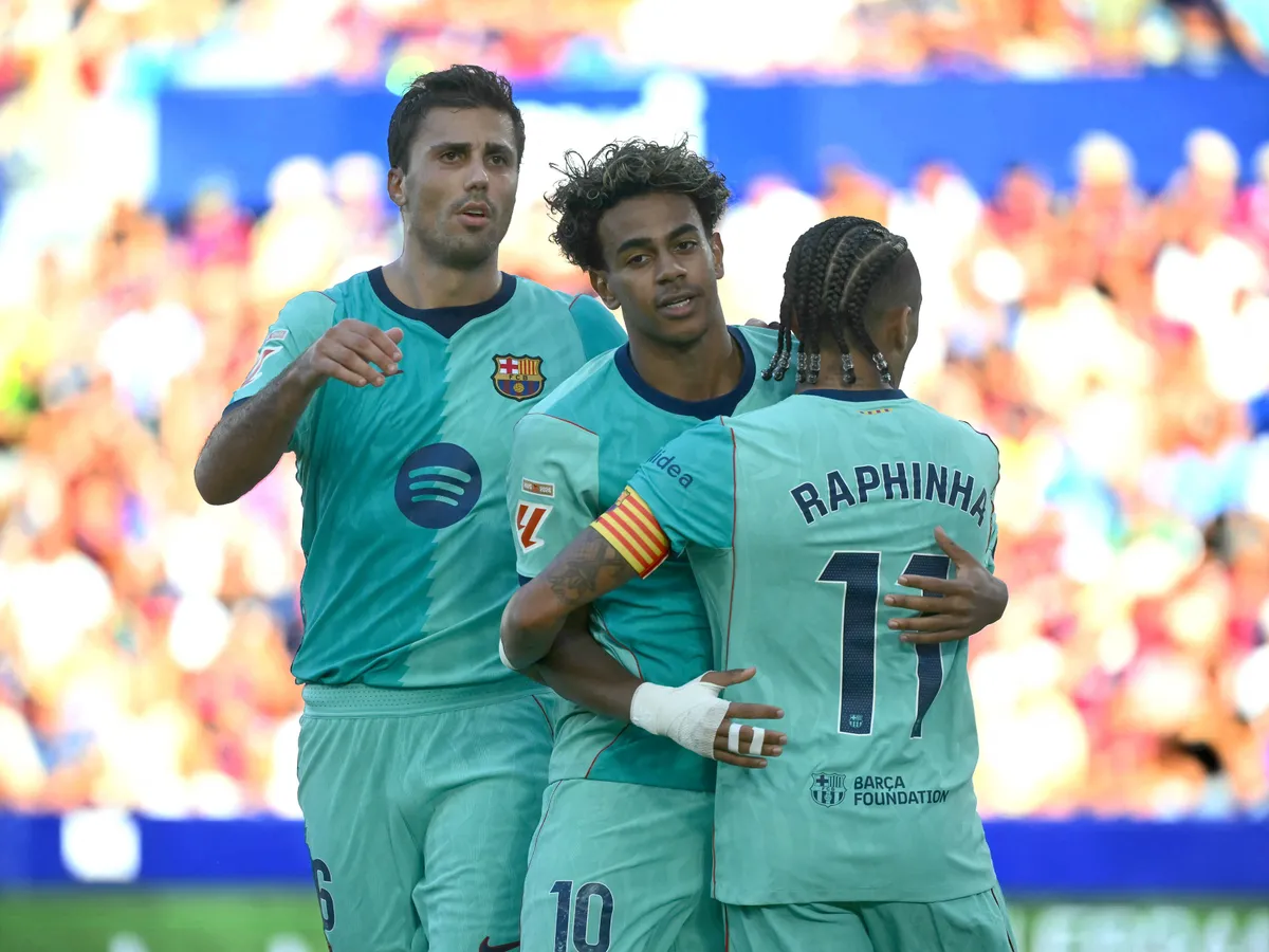 Barcelona's Spanish forward #10 Lamine Yamal celebrates with Barcelona's Brazilian forward #11 Raphinha and Barcelona's Spanish midfielder #16 Rodrigo scoring his team's third goal from the penalty spot during the Spanish league football match between Levante UD and FC Barcelona at Ciutat de Valencia Stadium in Valencia on September 13, 2026. (Photo by JOSE JORDAN / AFP)
