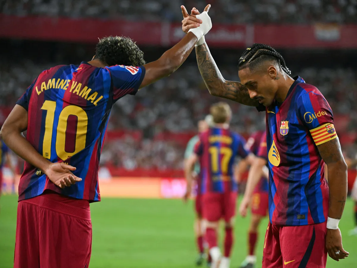 Barcelona's Brazilian forward #11 Raphinha (R) celebrates with teammate Spanish forward #10 Lamine Yamal after scoring his team's second goal during the Spanish league football match between Sevilla FC and FC Barcelona at the Ramon Sanchez Pizjuan stadium in Seville on September 19, 2026. (Photo by JORGE GUERRERO / AFP)