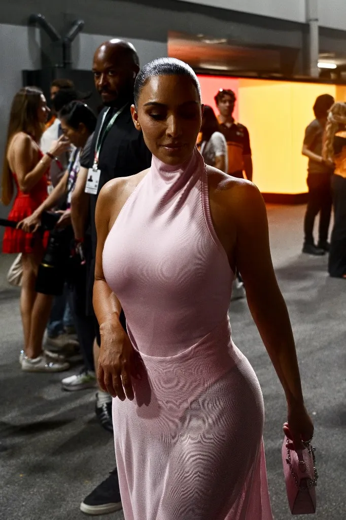 US social media personality and businesswoman Kim Kardashian (C) walks before the start of the qualifying session ahead of the Formula One Singapore Grand Prix at the Marina Bay Street Circuit in Singapore on October 10, 2026. (Photo by ANTHONY WALLACE / AFP)