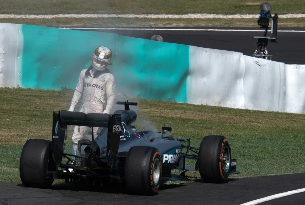 Mercedes AMG Petronas F1 Team's British driver Lewis Hamilton leaves his car after flames appeared at the back of his car after the engine exploded during the Formula One Malaysian Grand Prix in Sepang on October 2, 2016. Daniel Ricciardo triumphed at the Malaysian Grand Prix, but his win was overshadowed by Lewis Hamilton's claim that he was the victim of a conspiracy aimed at halting his march to a fourth world title. Hamilton was leading with 15 laps to go when the engine on his Mercedes spectacularly exploded at the Sepang International Circuit. (Photo by C.L.DONALD LIM / AFP)